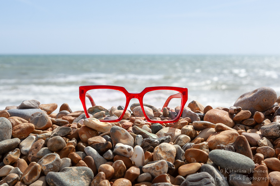 red frames (glasses) on Brighton beach pebbles with the sea in the background